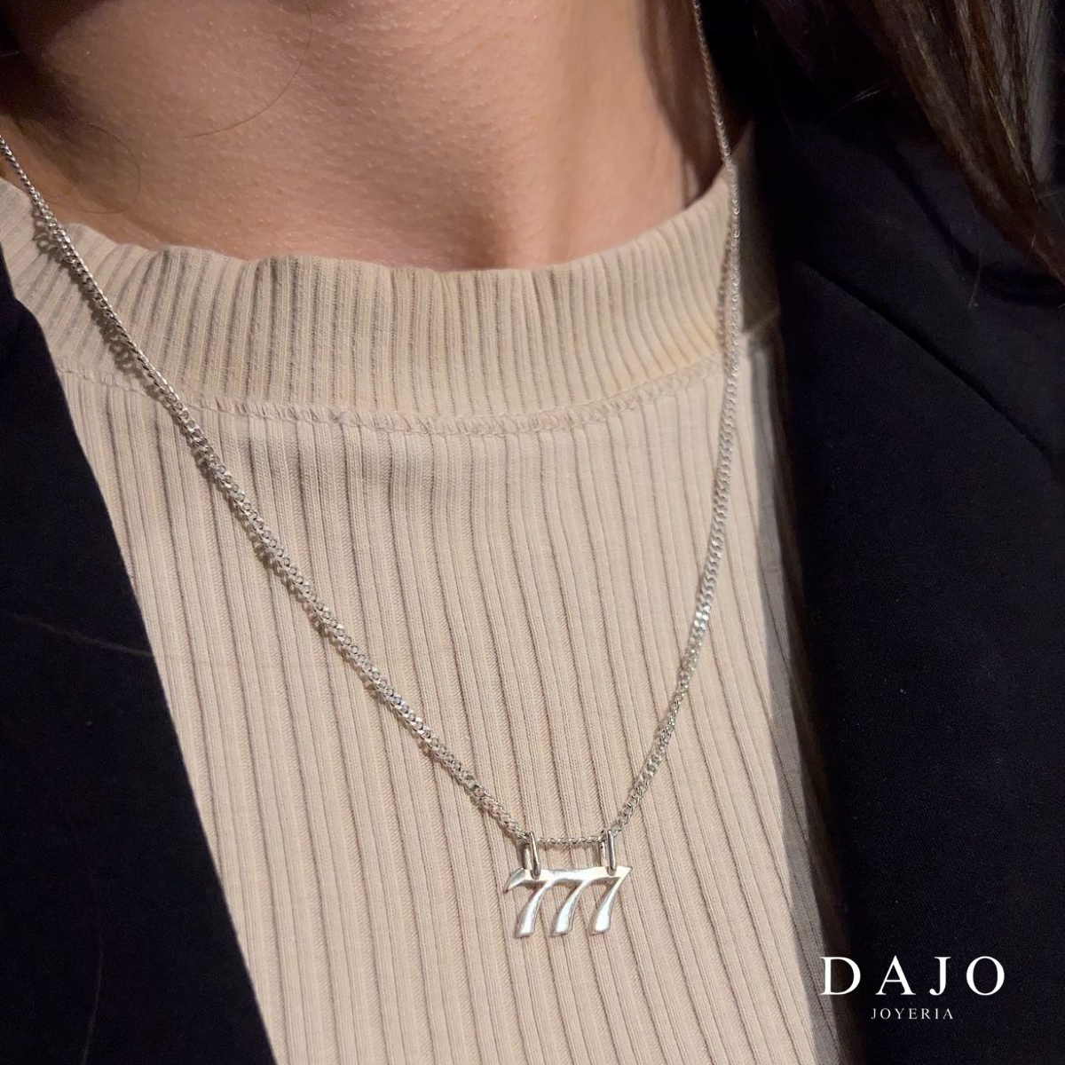 Mujer con el Dije Número Ángel 777 de plata .925 de DAJO en una cadena, sobre un suéter beige