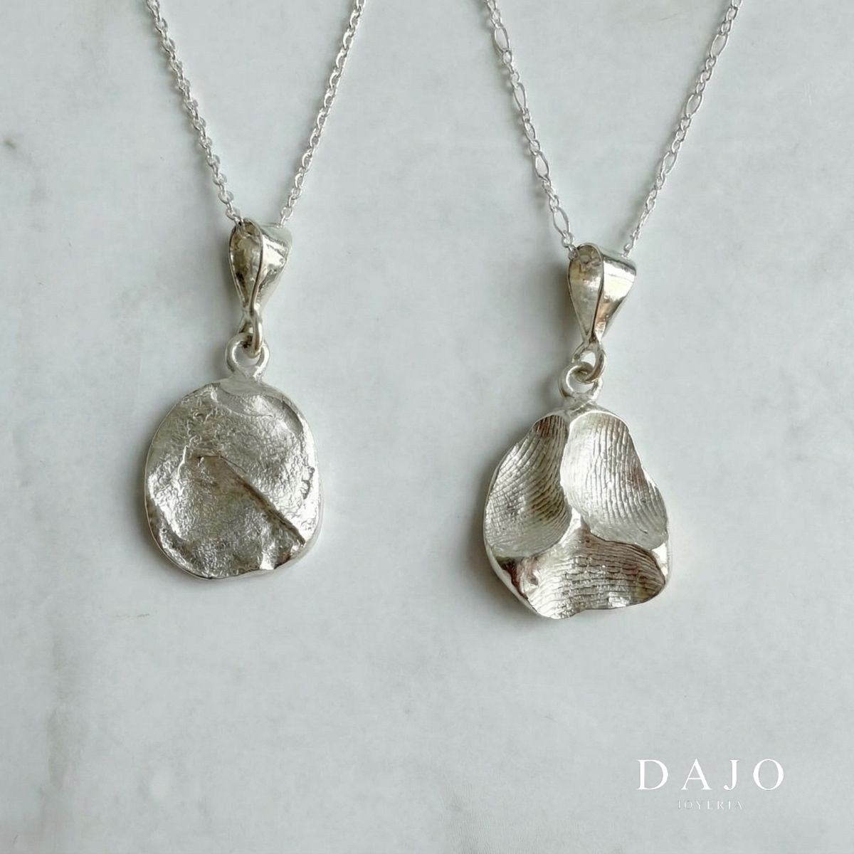 Dije Huella Doble de plata .925: dos dijes con una huella dactilar real cada uno, colgados de sus cadenas sobre mármol, de DAJO Joyería
