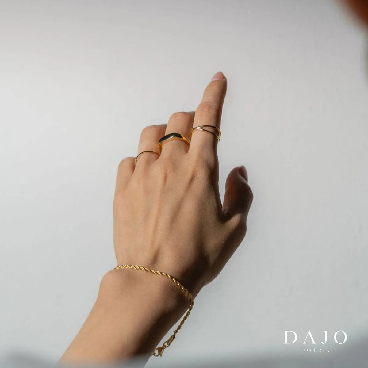 Mano modelo mujer luciendo set conjunto layering anillos y pulsera de oro sólido Proyectando elegancia y distinción.