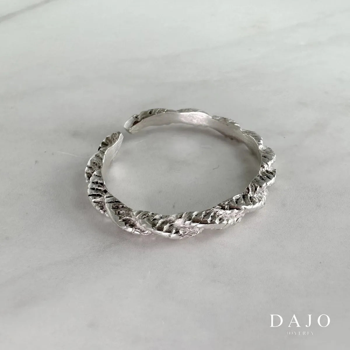 Joyería Anillo de plata .925 estilo minimalista elegante formal diseño ajustable artesanal mexicano con forma de torzal entrelazado en fondo mármol gris