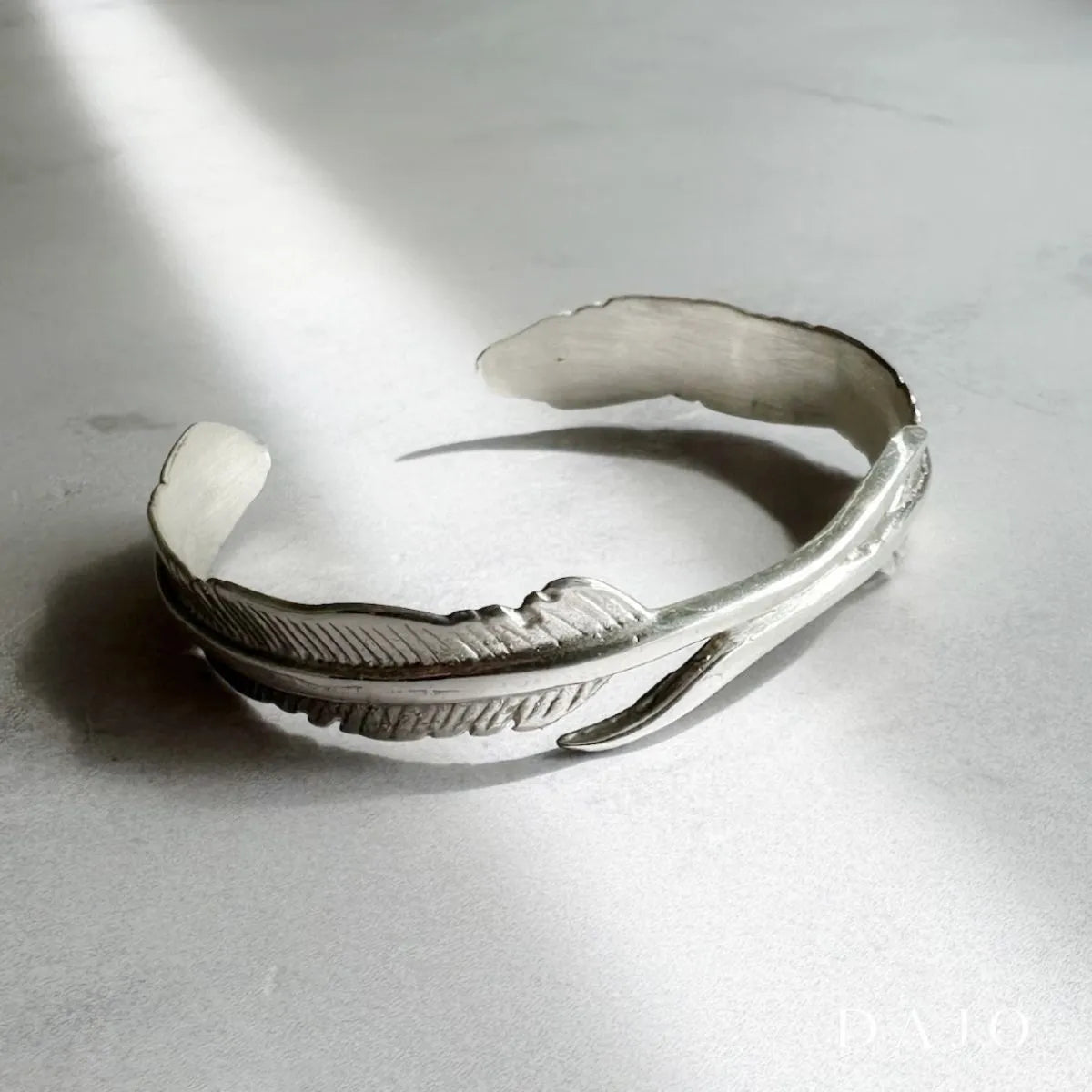Brazalete de plata en forma de plumas de ave en plata .925
Presenta dos plumas que se cruzan con elegancia en forma de “U”, uniendo sus cálamos como símbolo de libertad, conexión y transformación. Inspirado en el minimalismo simbólico y el lujo silencioso, es una pieza que habla sin alzar la voz