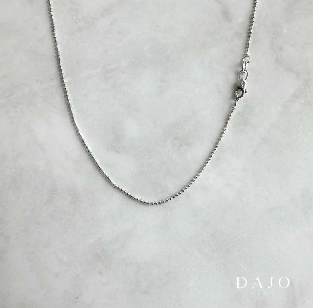Esta cadena de plata .925 está formada por pequeñas esferas de 1 mm con caras planas, lo que le da un brillo extra al moverse (como un mini dodecaedro).
Es delgada, minimalista y con un toque original gracias a su textura poco común.
Ideal si buscas una cadena sutil, diferente y que atrape la luz de forma elegante