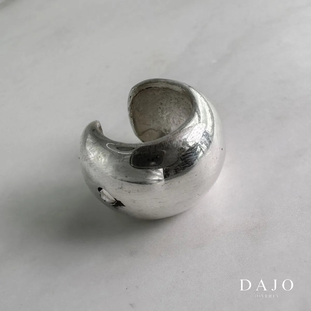Este earcuff de plata .925 se ajusta cómodamente a tu oreja sin necesidad de perforaciones, permitiéndote experimentar con tu estilo de manera versátil. Inspirado en el "Cloud Gate" de Chicago, también conocido como "The Bean", una escultura elíptica de acero inoxidable que refleja el cielo y el entorno urbano. Incorpora una pieza llamativa y contemporánea que refleja modernidad y sofisticación, elevando tu estilo con un toque artístico y distintivo