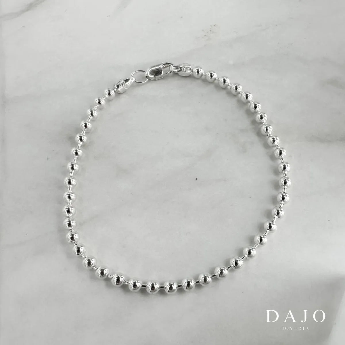 Esta pulsera de plata .925 está compuesta por esferas de 2 mm de diámetro, un diseño que equilibra elegancia y presencia con un estilo moderno.
El patrón continuo de esferas crea un movimiento visual suave y atractivo, ideal para quienes buscan una pieza sutil pero con un poco más de carácter.