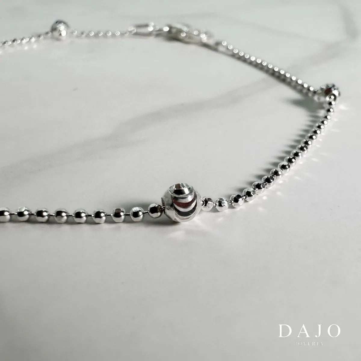 Esta pulsera de plata .925 presenta un diseño exclusivo que alterna esferas de 1 mm con esferas de 2 mm distribuidas a lo largo de la cadena, creando un patrón inspirado en las constelaciones estelares. Este estilo poco común aporta un toque de elegancia minimalista y sofisticación a tu atuendo