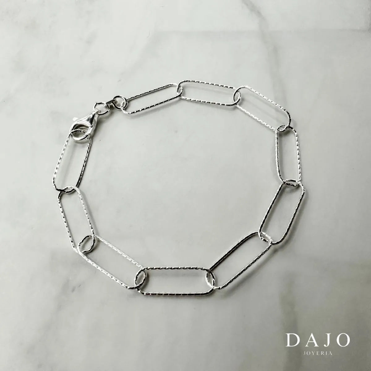 Esta pulsera de plata .925 está compuesta por eslabones rectangulares largos y delgados con un acabado diamantado: un relieve sutil en la plata que refleja la luz con brillo facetado.
Con 5 mm de grosor, es una pieza ligera pero visualmente impactante.
Llévala para proyectar elegancia y sofisticación con un toque brillante y moderno