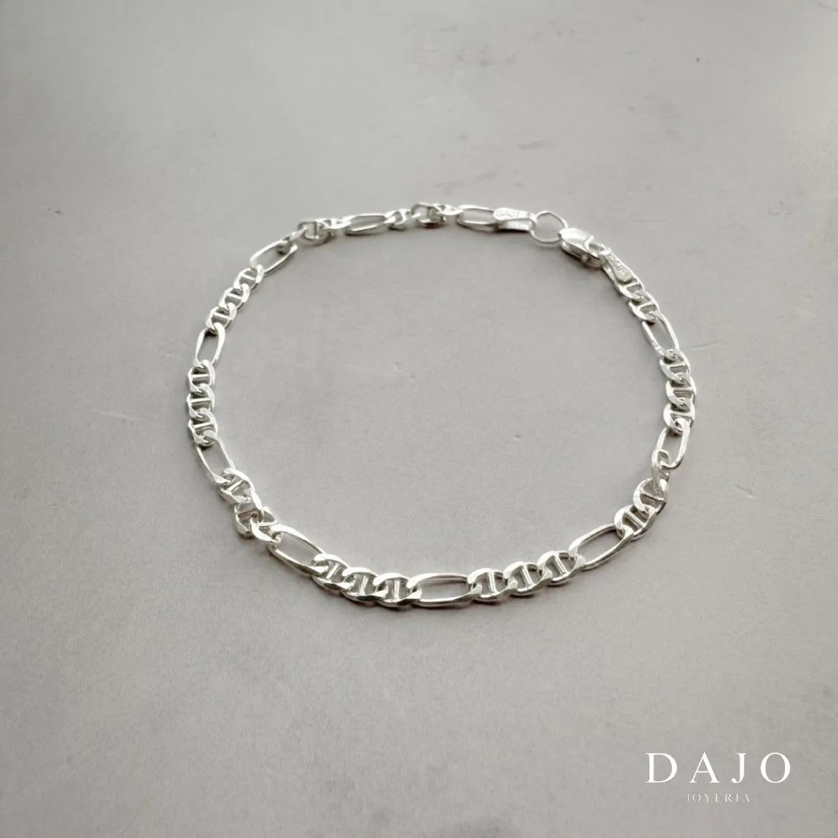 Esta pulsera de plata .925 presenta el clásico diseño de eslabones marineros, también conocidos como "eslabones de ancla". Cada eslabón ovalado cuenta con una barra central horizontal, evocando las cadenas utilizadas en las anclas náuticas. Con un grosor de 2 mm, esta pieza ofrece una apariencia delicada y elegante