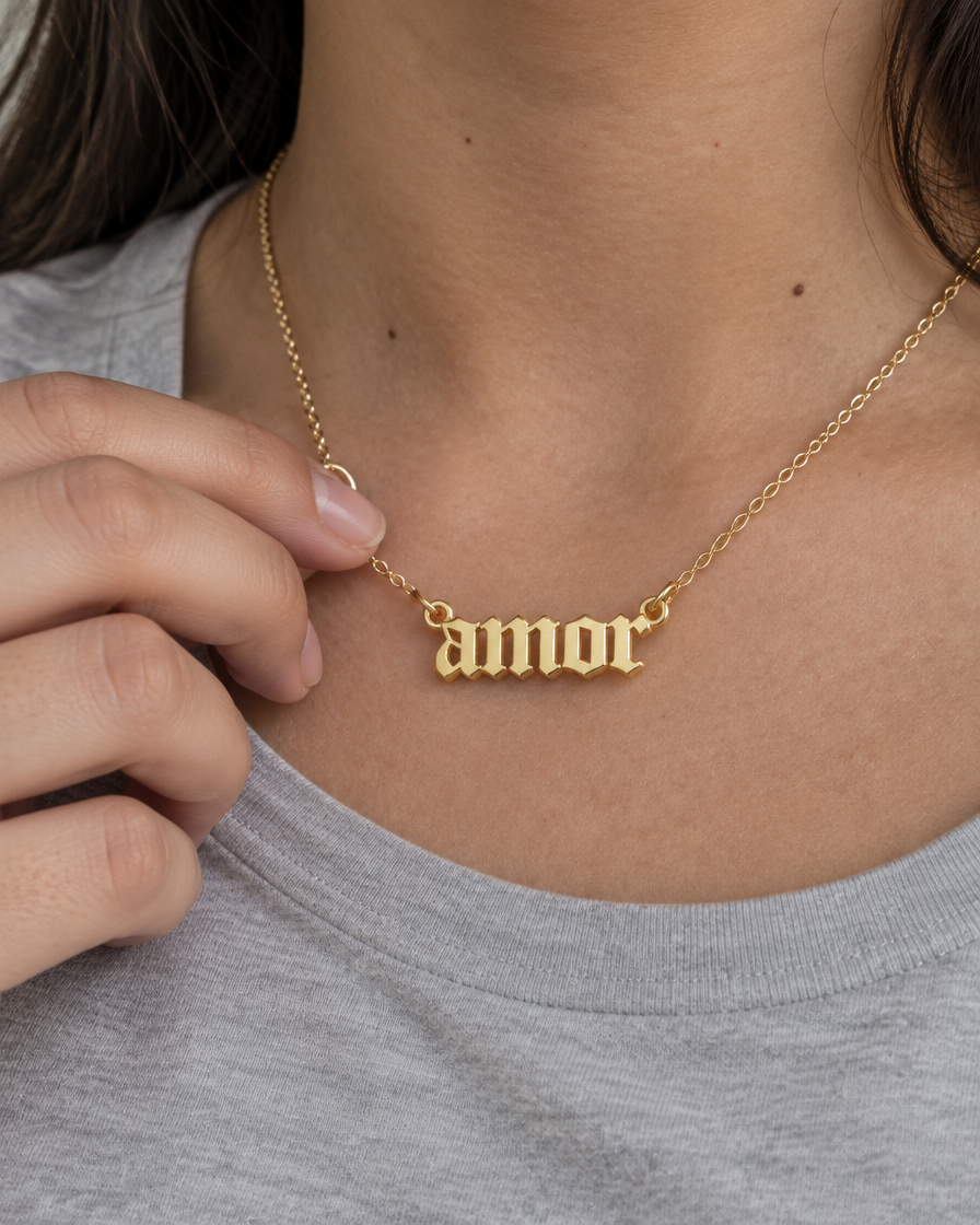 Dije Amor de oro sólido de DAJO puesto sobre una playera gris
