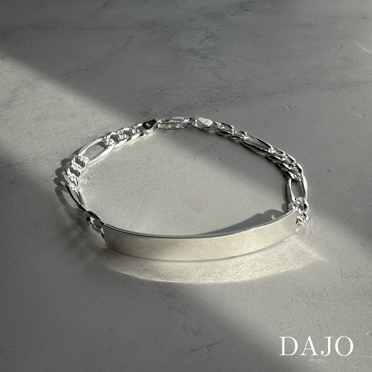 Esta pulsera de plata .925 combina eslabones estilo Cartier o Fígaro con una placa central rectangular de 18 mm por 50 mm, perfecta para grabar nombres, fechas o mensajes especiales.
Los eslabones Fígaro, originarios de Italia, alternan patrones de eslabones cortos y largos, aportando un diseño distintivo y elegante.