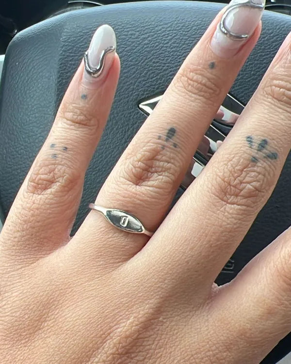 Mano con el anillo Botánica con inicial puesto