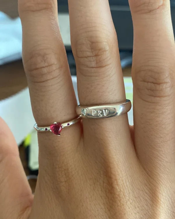 Mano con el anillo Botánica con inicial junto a otro anillo