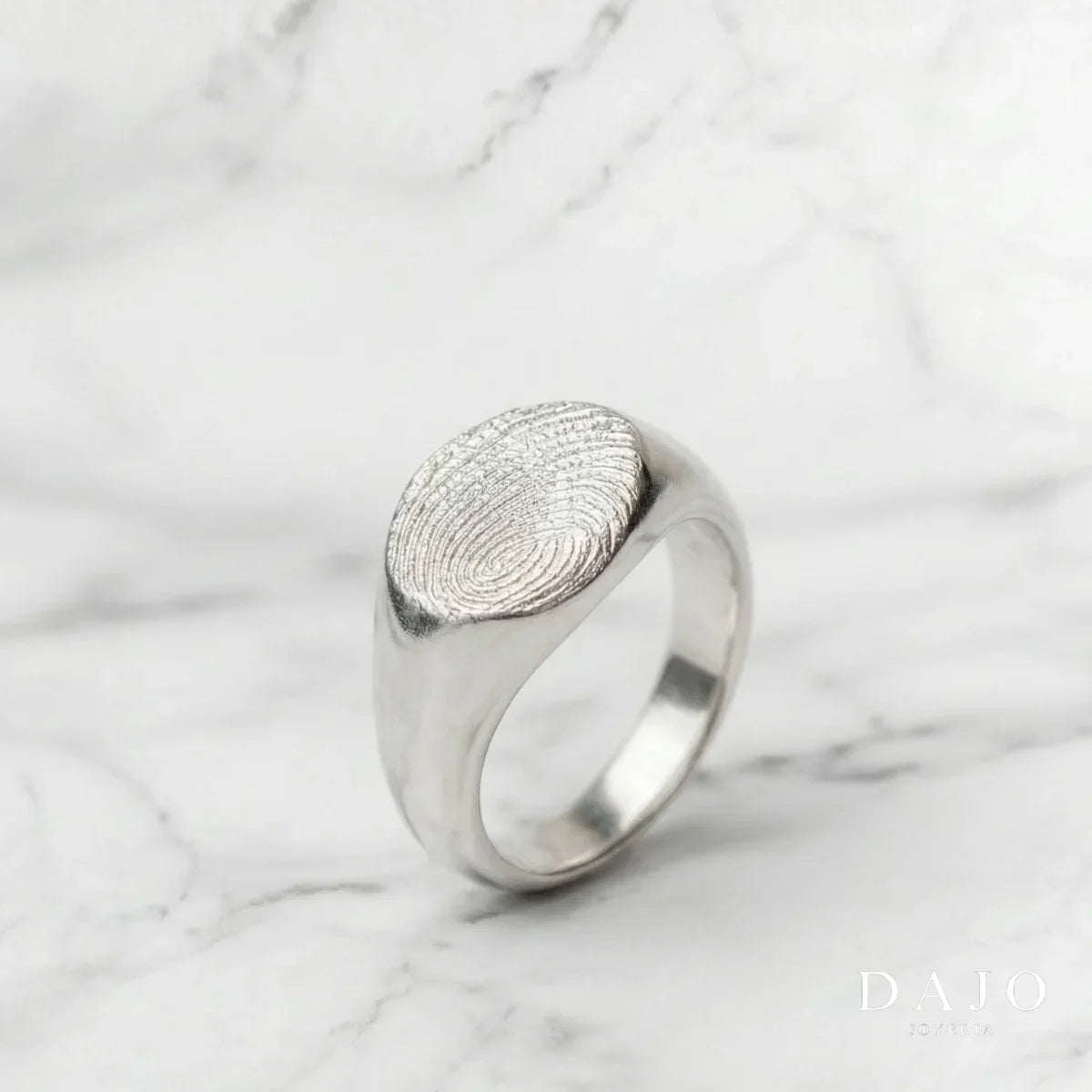 Anillo Huella Redondo de plata .925 con una huella dactilar en relieve, sobre mármol blanco