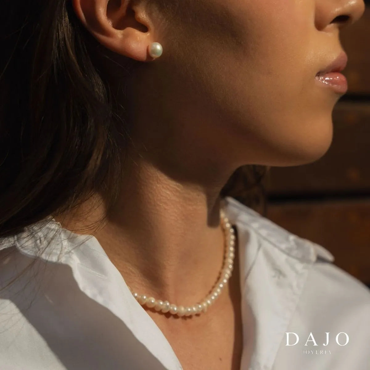 Modelo luciendo collar de perlas cultivadas con detalles en plata .925. La pieza realza un atuendo elegante, transmitiendo gracia y distinción
