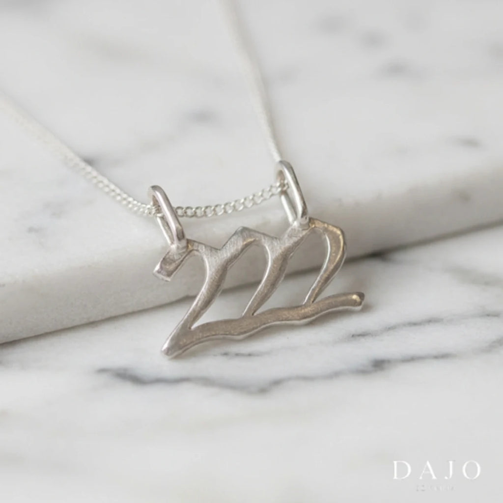 Dije Número Ángel 222 de plata .925 con su cadena, sobre mármol | DAJO