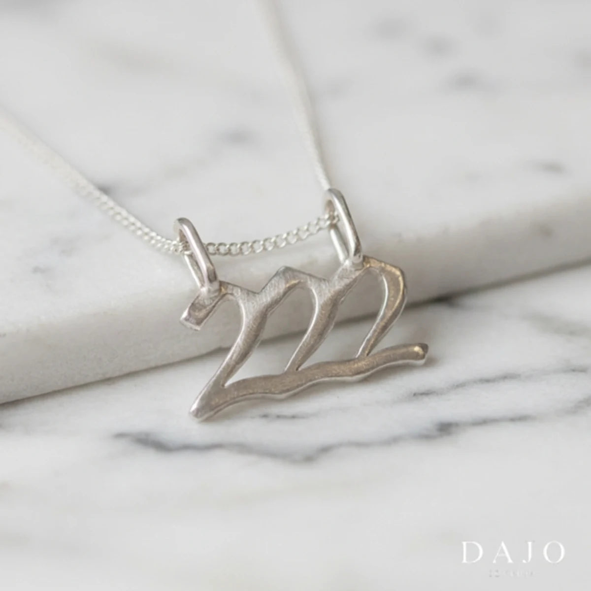 Dije Número Ángel 222 de plata .925 con su cadena, sobre mármol | DAJO