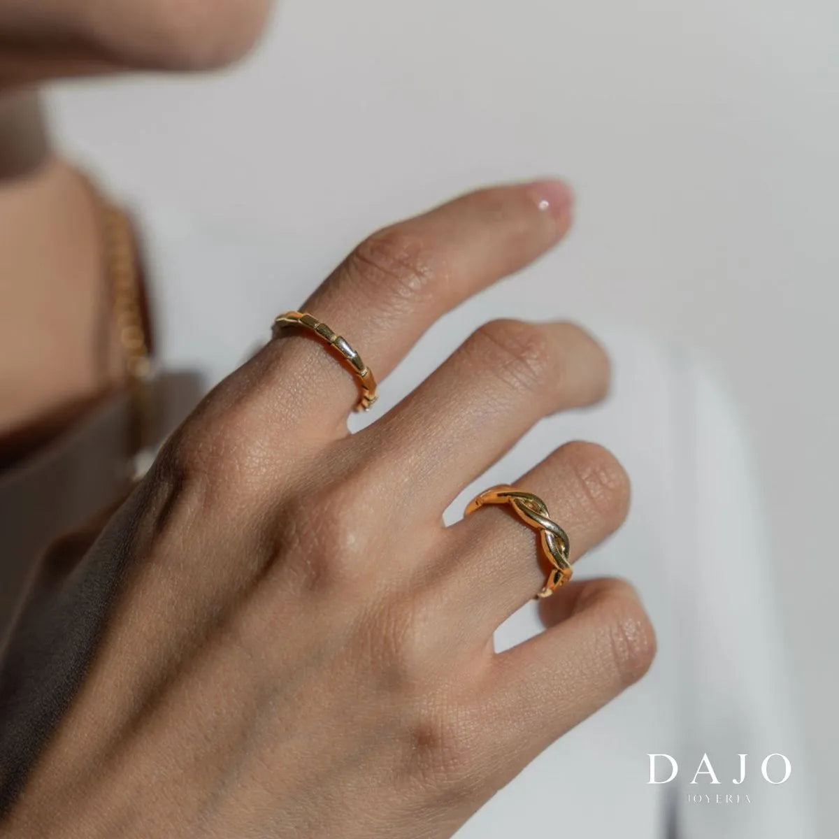 Mano modelo mujer usando dos anillos de Oro elegante fondo blanco