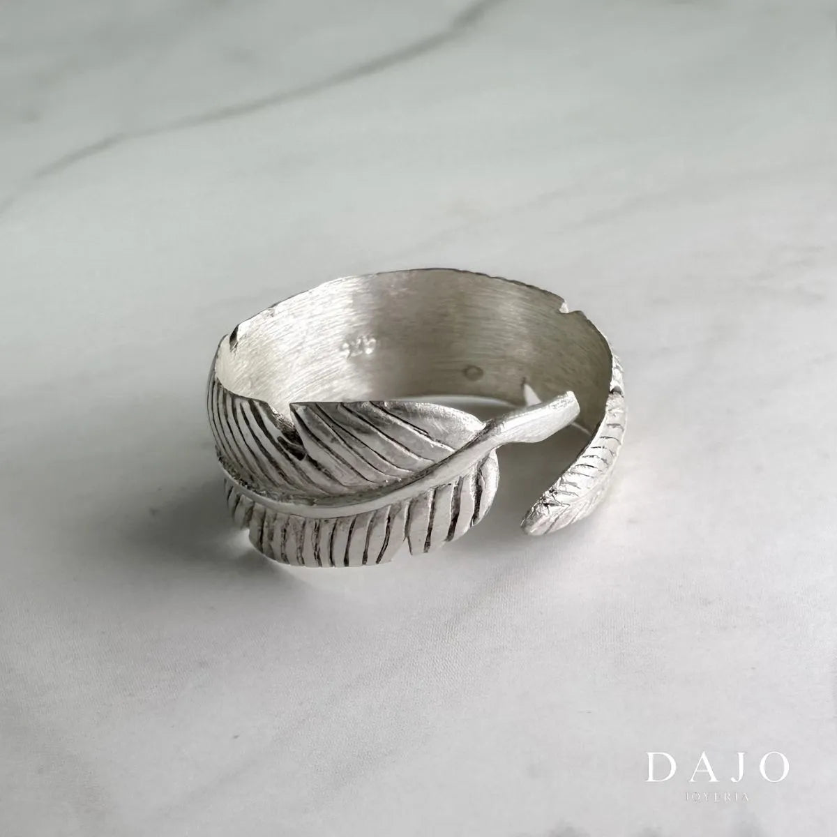 Anillo pluma de plata .925, destacando la delicadeza y la ligereza de su diseño abierto y ajustable.