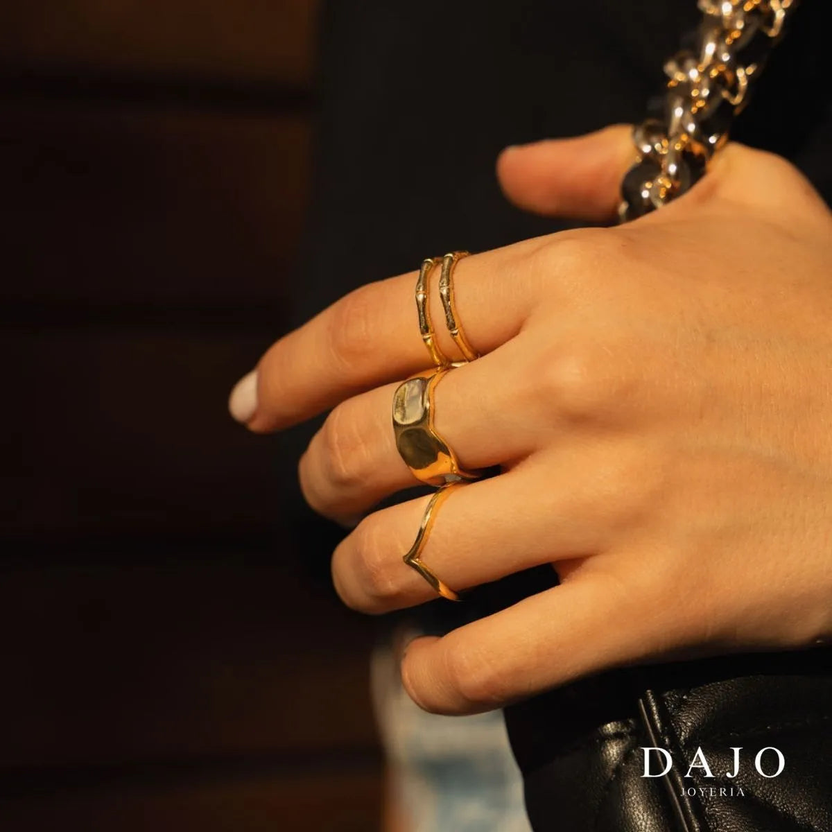 Modelo mujer usando combinación set de joyería anillos y cadenas Oro Vermeil plata .925 con baño de oro de 14K quilates estilo urbano caminando con bolso