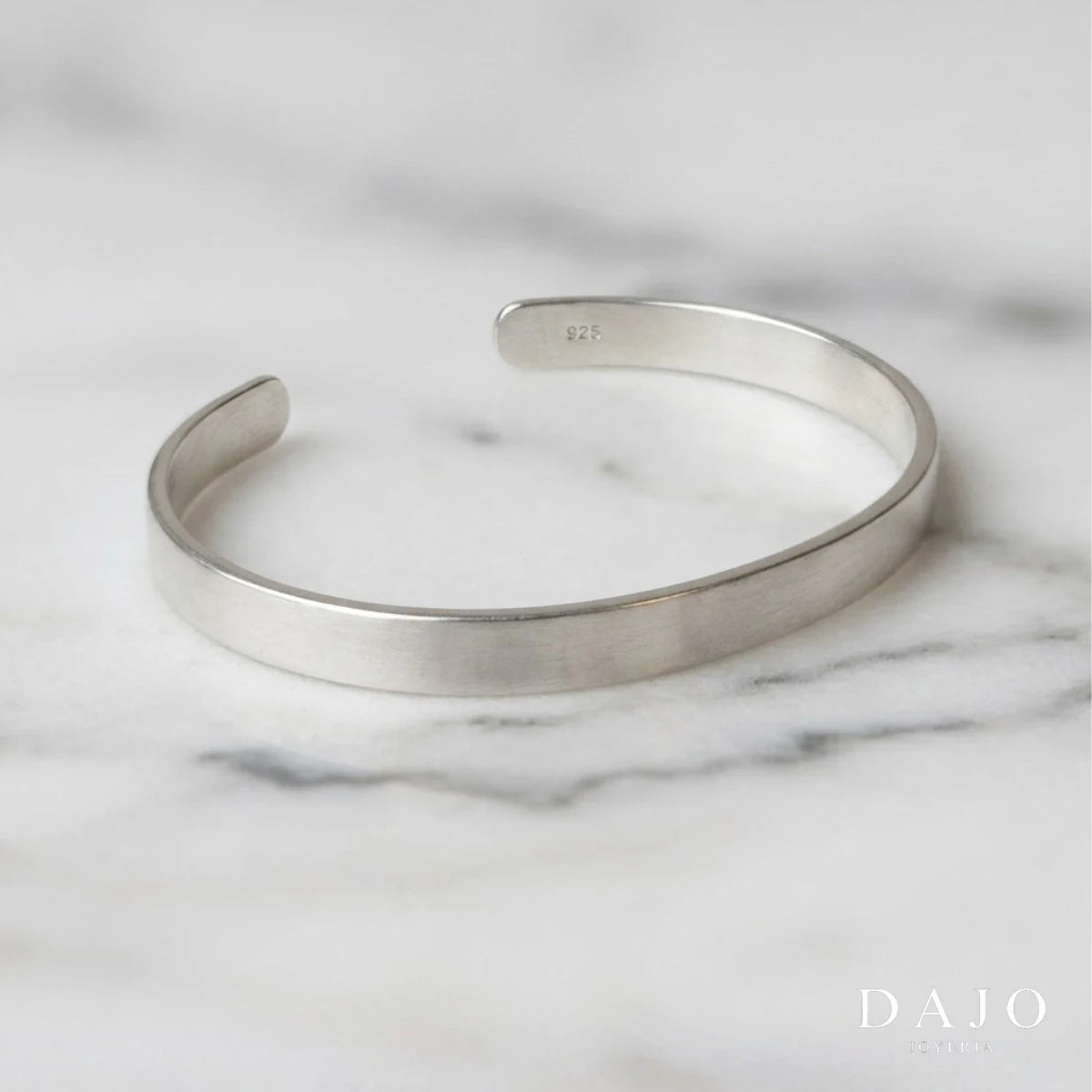 Este brazalete en plata .925, con su diseño en forma de "U" y un ancho de 6 mm, encarna la esencia del minimalismo estético: líneas limpias y funcionalidad sin adornos superfluos. Su elegancia discreta resuena con la estética "old money", que valora la sofisticación atemporal y la calidad sobre la ostentación. La pieza proyecta una imagen de refinamiento y buen gusto, ideal para quienes aprecian la moda clásica y la artesanía de alta calidad