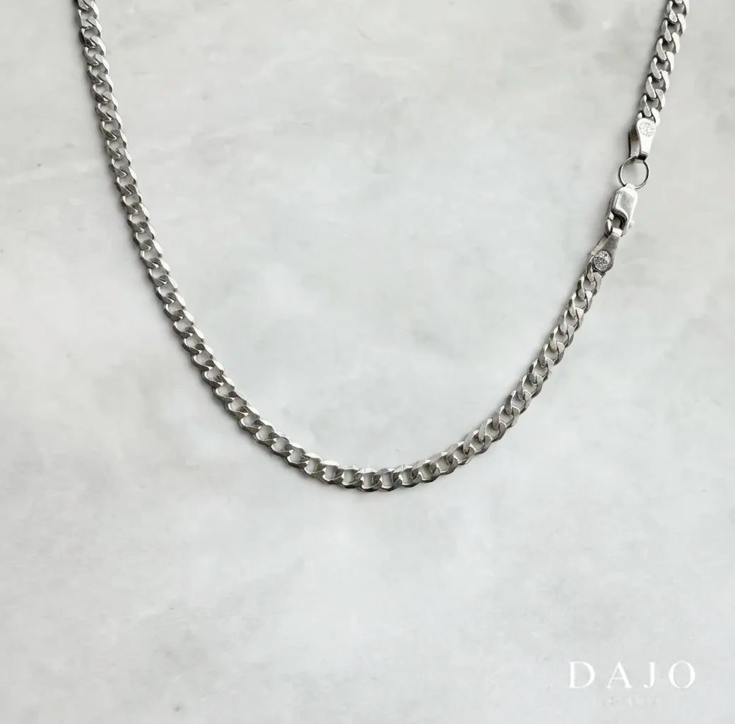 Esta cadena de plata .925 con eslabones barbados de 3 mm ofrece un balance perfecto entre elegancia clásica y presencia discreta.
Su diseño tradicional aporta solidez sin caer en la ostentación.&nbsp;Una joya sobria y atemporal que proyecta seguridad y estilo.