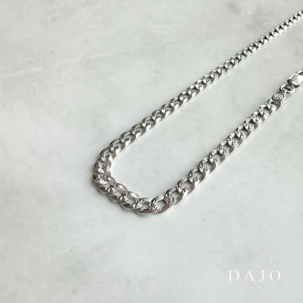 Con eslabones tipo barbado y un ancho de 5 mm, esta cadena de plata .925 impone con elegancia y solidez.
Su diseño clásico, presente en estilos que van del old money al urbano refinado, proyecta confianza, estructura y poder contenido.
Ideal para quienes buscan una pieza con peso visual y carácter atemporal