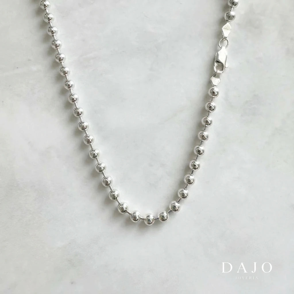 Esta cadena de plata .925 está hecha con esferas de 3 mm unidas entre sí, lo que le da un look único, parecido a pequeñas perlas metálicas.
Tiene una presencia llamativa pero sin exagerar, ideal si buscas algo elegante con un toque diferente.&nbsp;Su diseño poco común la hace perfecta para destacar sin perder ese estilo minimalista y moderno
