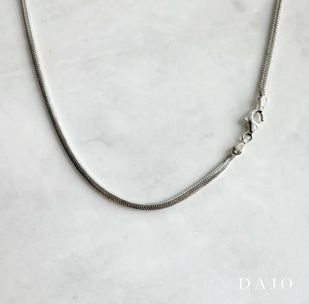 Hecha en plata .925, esta cadena de 3 m de grosor tiene un diseño entrelazado de pequeños rectángulos diagonales que recuerdan las escamas de una serpiente.
Representa transformación, renovación y poder personal.