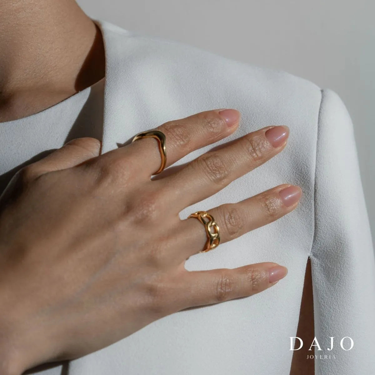 Modelo mujer usando combinación set de joyería anillos Oro Vermeil plata .925 con baño de oro de 14K quilates estilo elegante traje blanco.  Mano en pecho