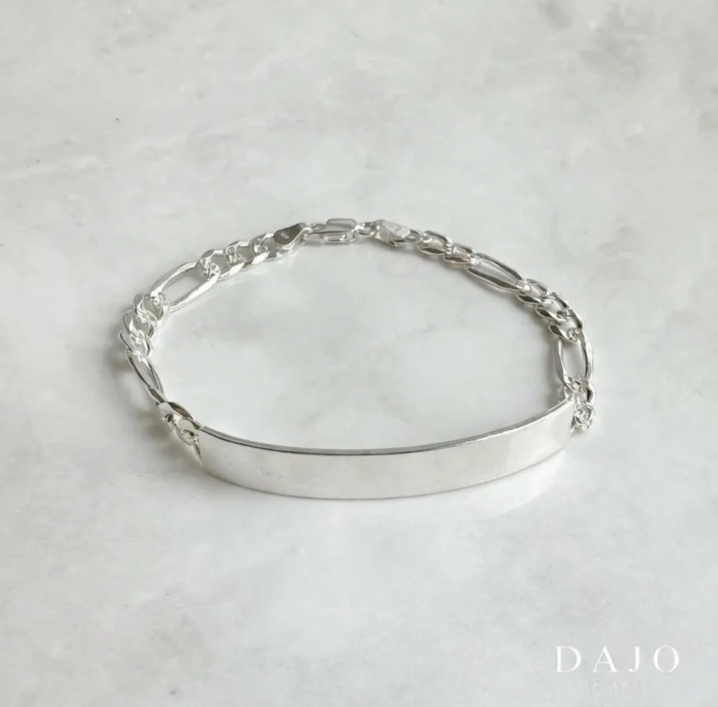 Esta pulsera de plata .925 combina eslabones estilo Cartier o Fígaro con una placa central rectangular de 18 mm por 50 mm, perfecta para grabar nombres, fechas o mensajes especiales.

Los eslabones Fígaro, originarios de Italia, alternan patrones de eslabones cortos y largos, aportando un diseño distintivo y elegante.
