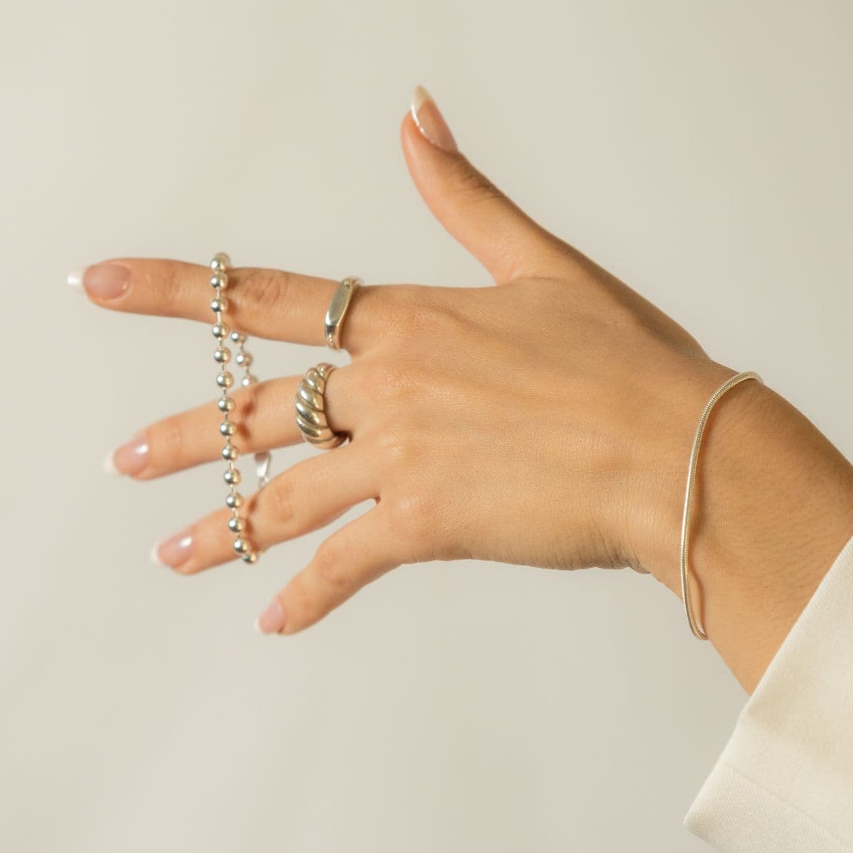 Manos de mujer mujer luciendo set combinación joyería Anillo de plata .925 estilo elegante artesanal mexicano con forma pan Croissant