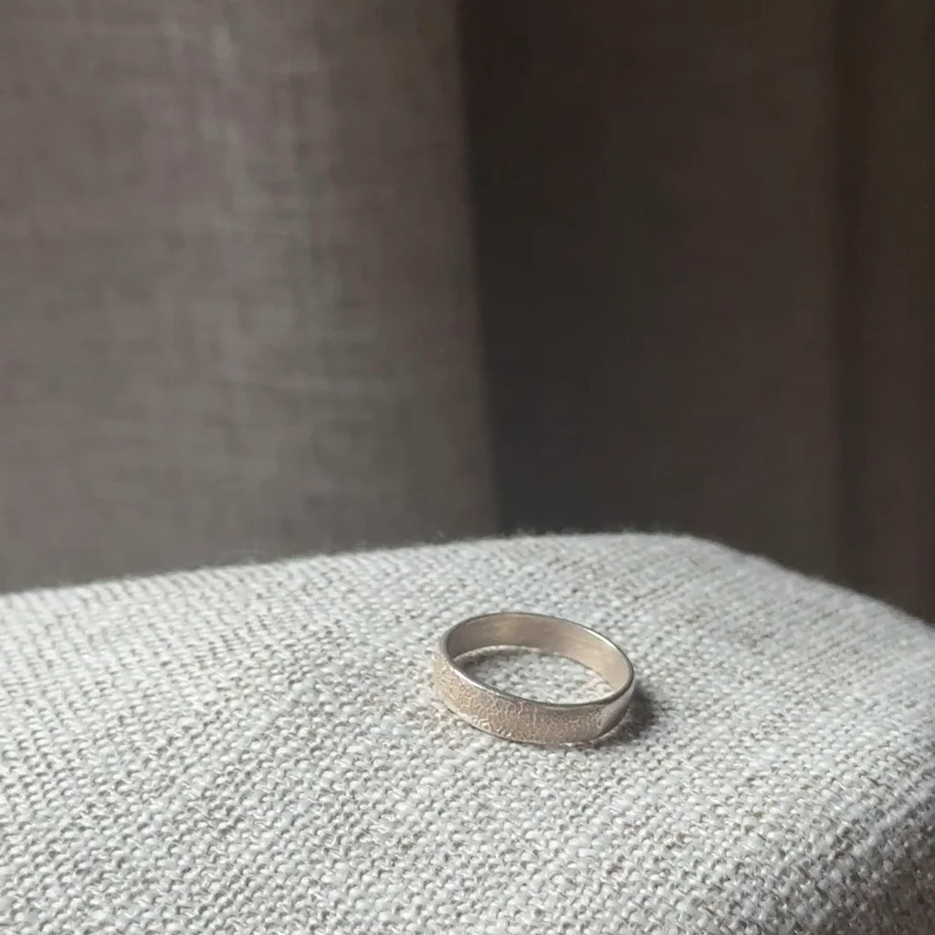 Anillo Huella Argolla de plata .925 en la mano, sobre un sillón