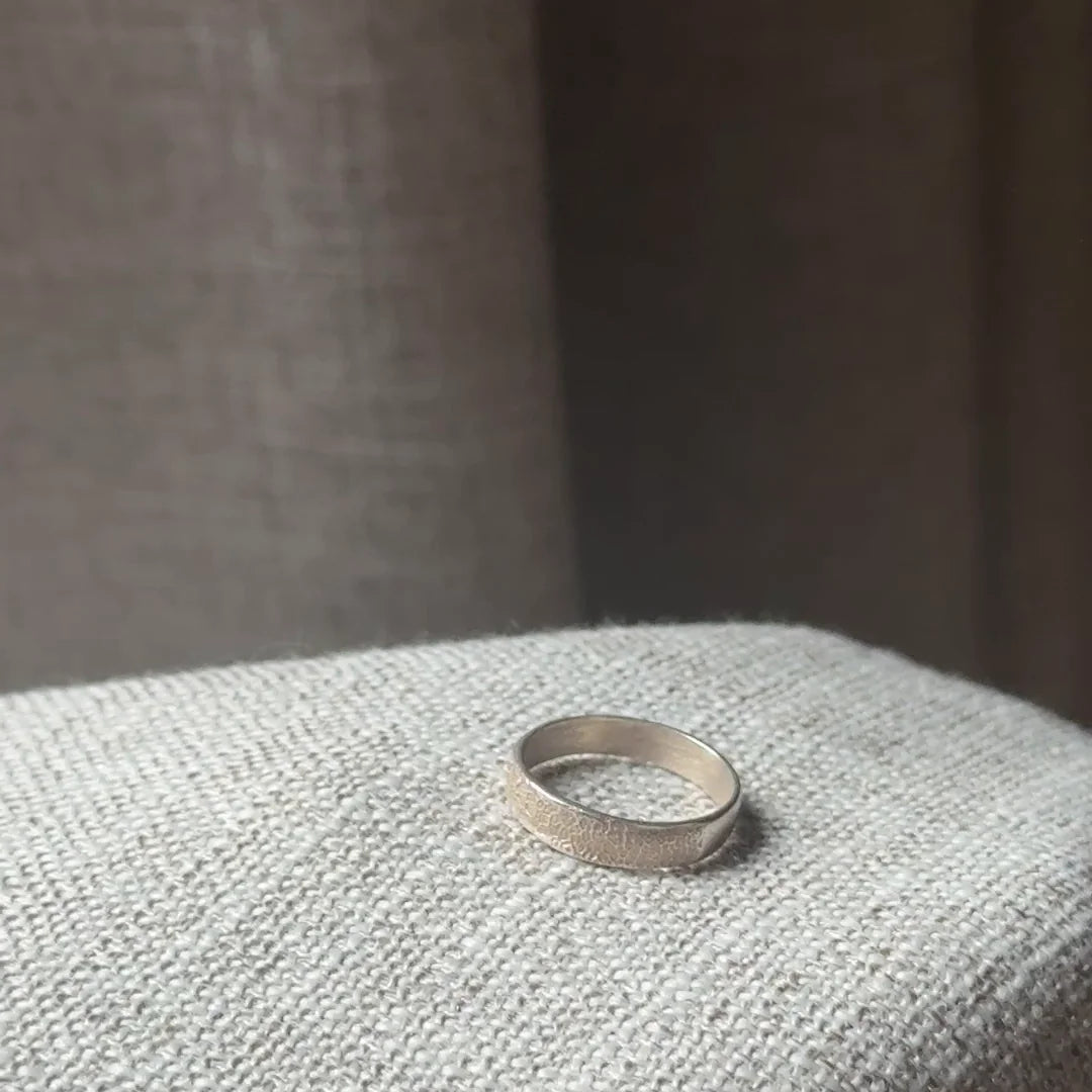 Anillo Huella Argolla de plata .925 en la mano, sobre un sillón