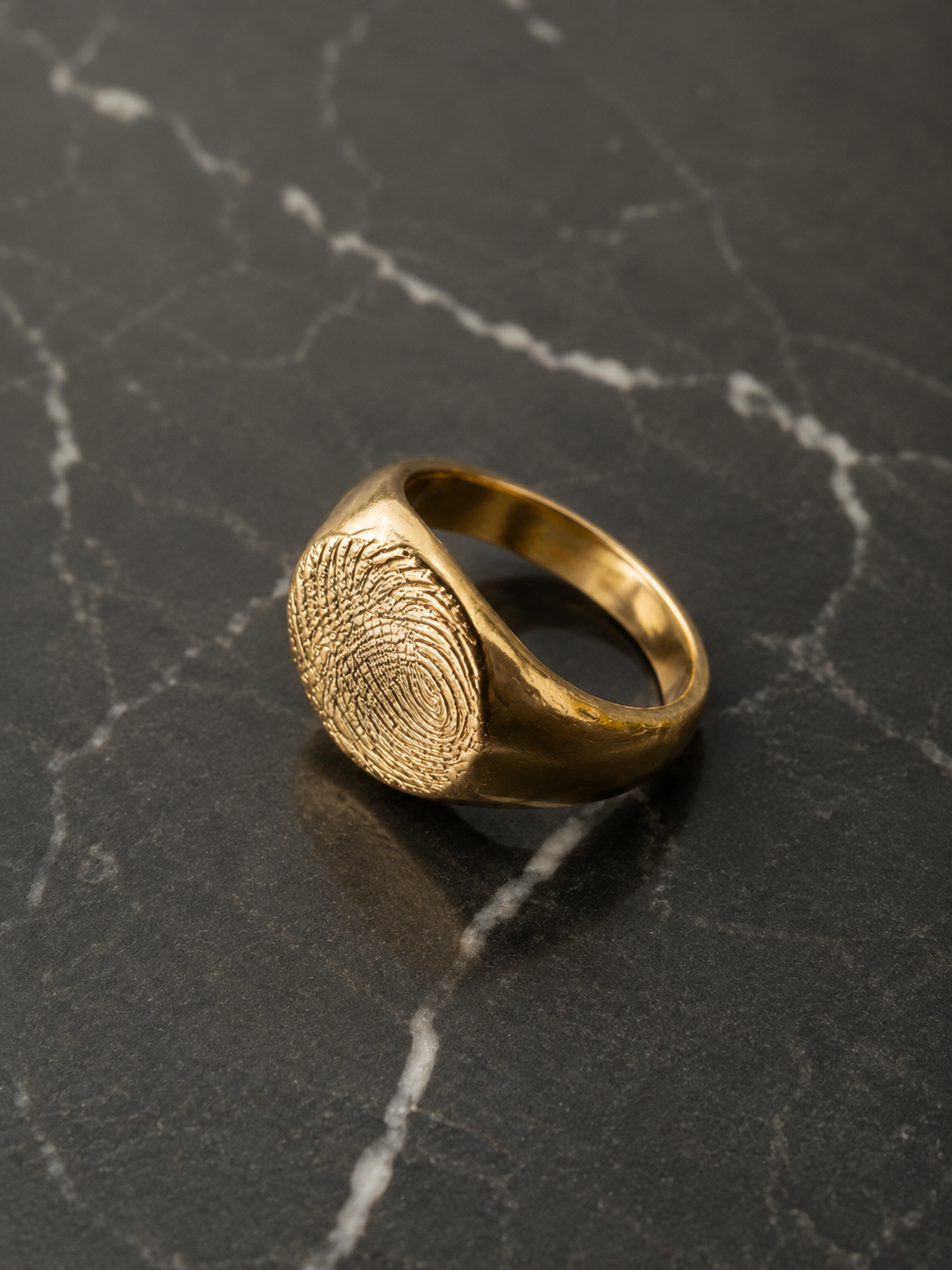 Anillo sello redondo con huella en oro solido sobre marmol negro - DAJO Joyeria