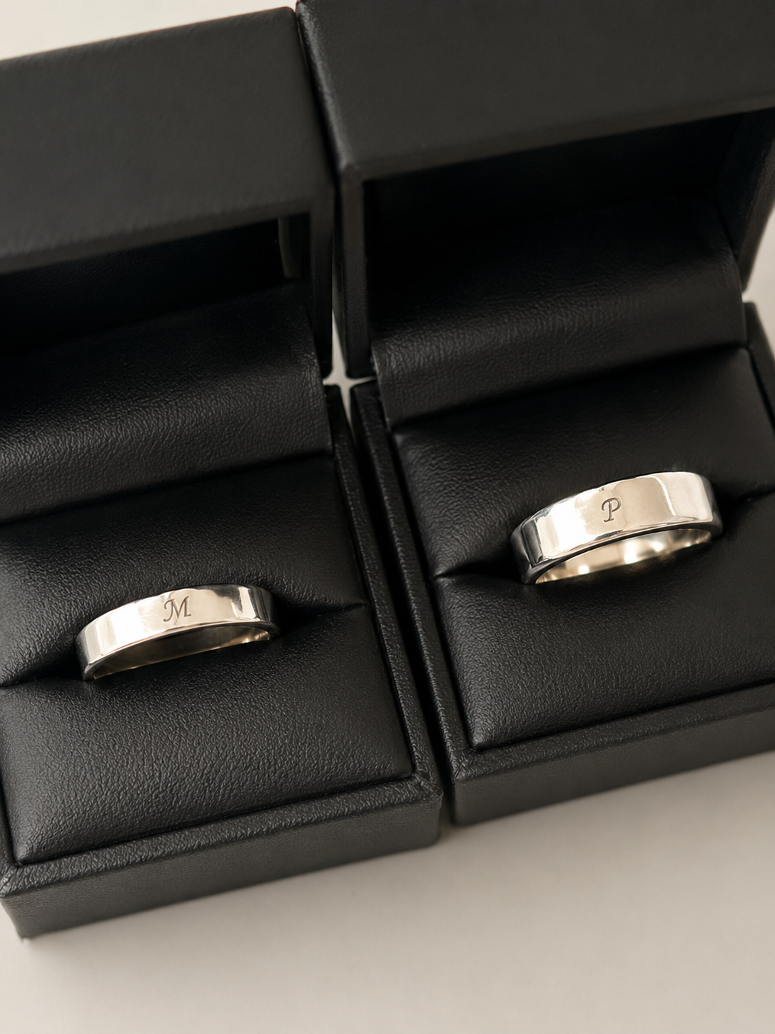 Dos anillos argolla de 4 mm en plata .925 con iniciales grabadas, en sus estuches DAJO