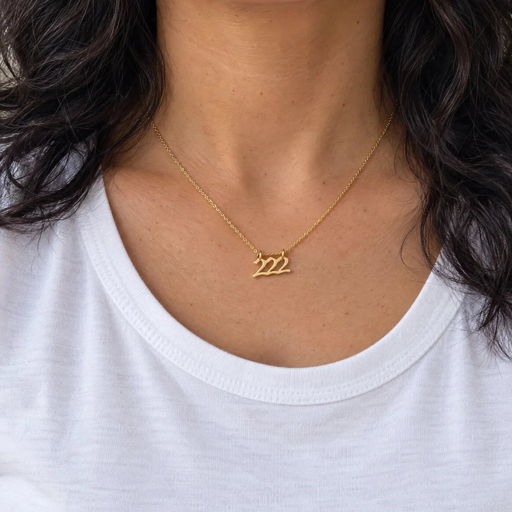 Dije Número Ángel 222 de oro sólido de DAJO puesto con playera blanca, a su tamaño real