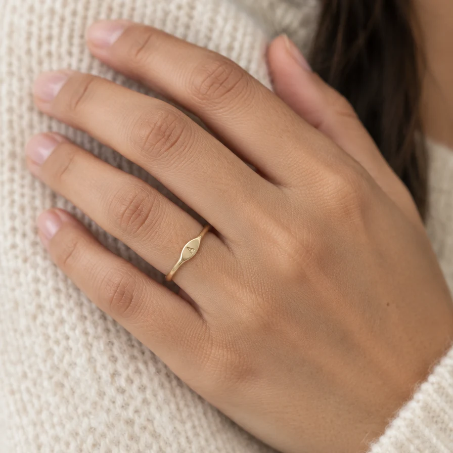 Anillo Botánica con Inicial de oro sólido de DAJO puesto en el dedo anular