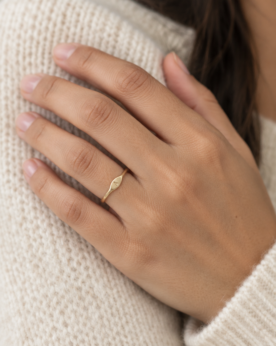 Anillo Botánica con Inicial de oro sólido de DAJO puesto en el dedo anular