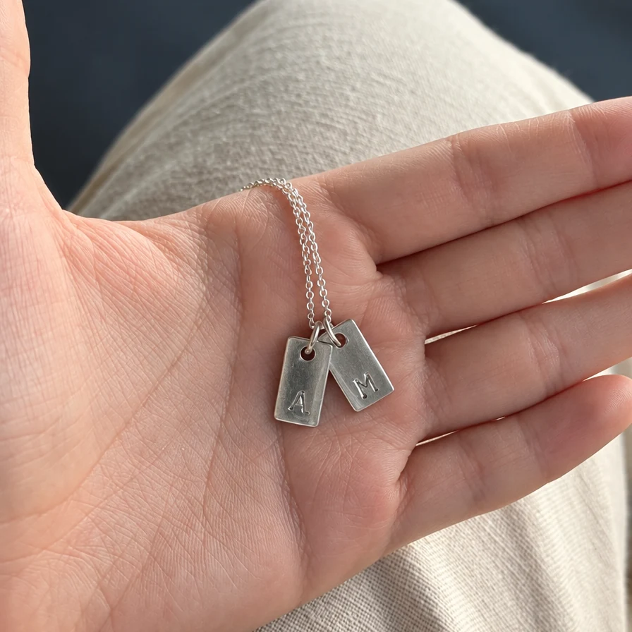 Dos dijes marco de plata en la palma de la mano: una inicial por cada uno, en la misma cadena - DAJO