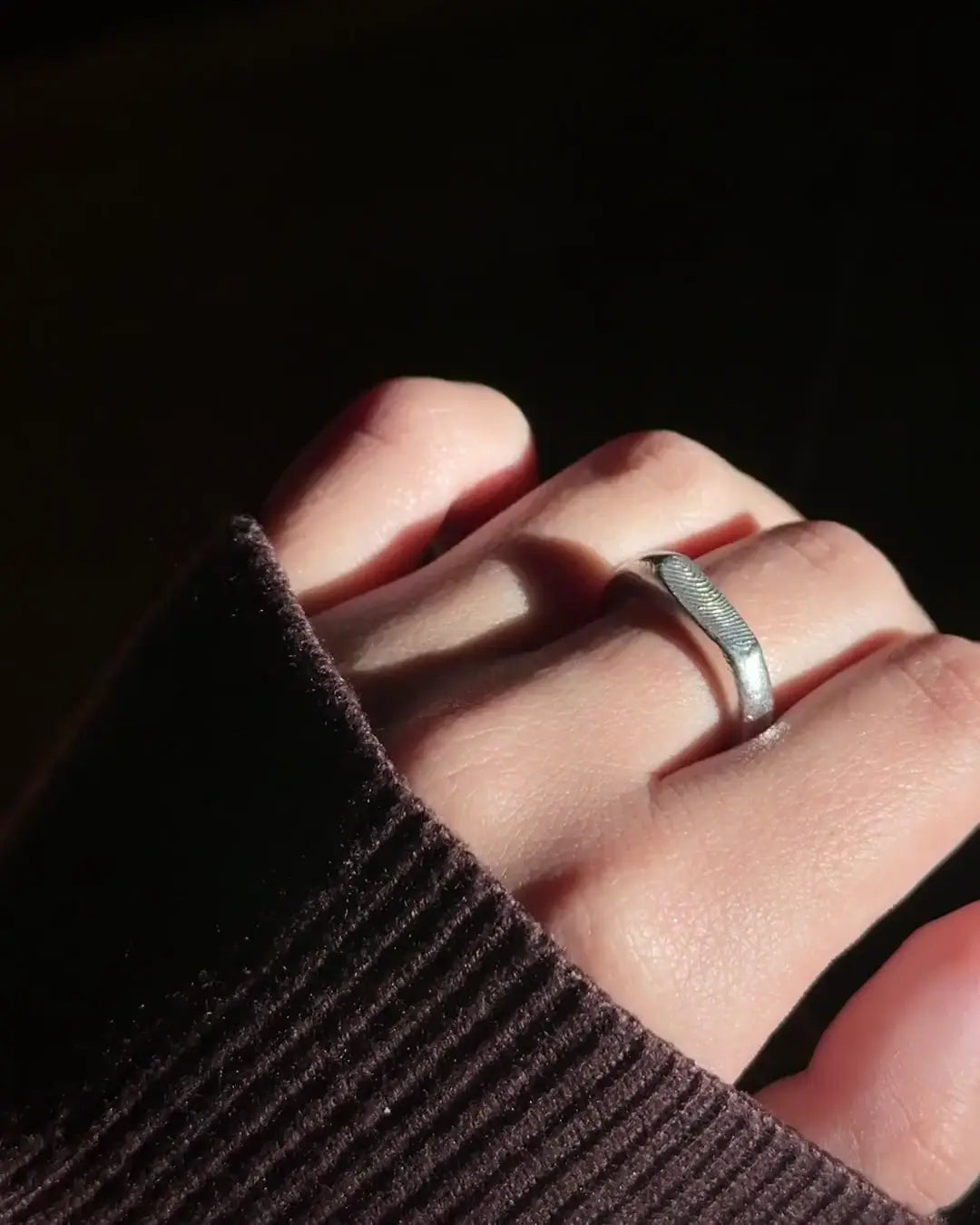 Mano con el Anillo Huella Rectangular de plata en luz de tarde