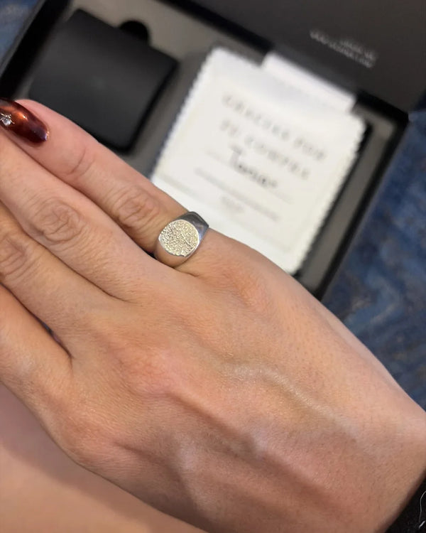 Anillo Huella Redondo puesto, con la caja negra de DAJO atrás
